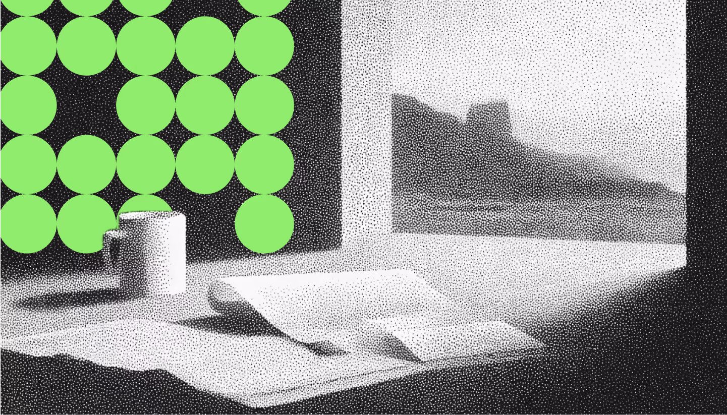 Black and white grainy image of a coffee mug and an open book on a table by a window with a mountain view poster.